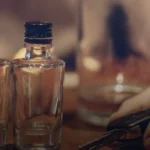 Two glass bottles and a hand holding car keys on a table.