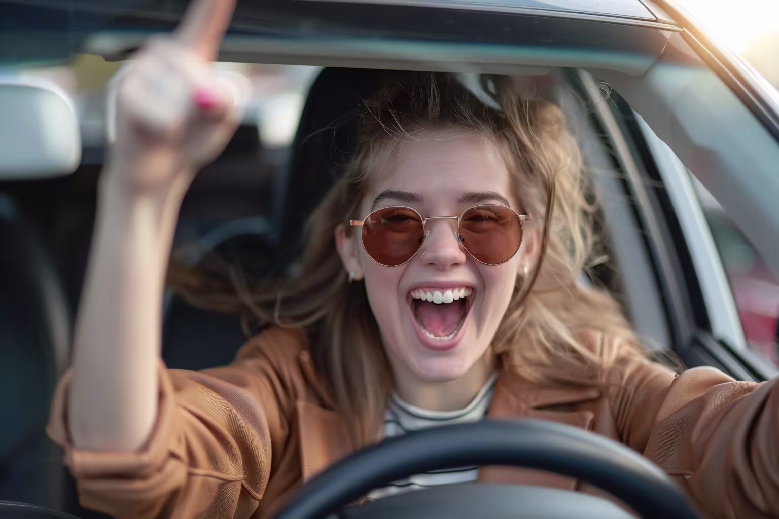 ChatGPT said: A young woman wearing sunglasses smiles and cheers while driving, with one hand on the wheel and the other raised.