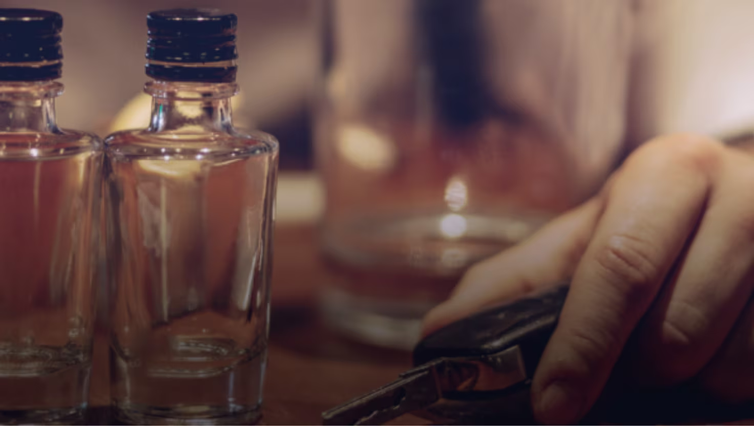 "Person with car keys and alcohol bottles on table, illustrating the dangerous drunk driving decision that leads to serious accidents and settlement claims in Texas
