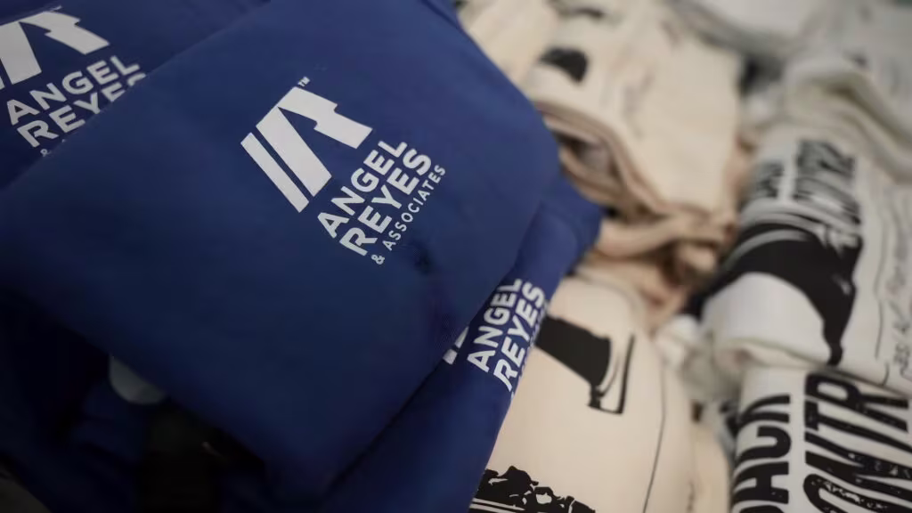 Angel Reyes & Associates personal injury law firm branded merchandise including blue cap and promotional materials