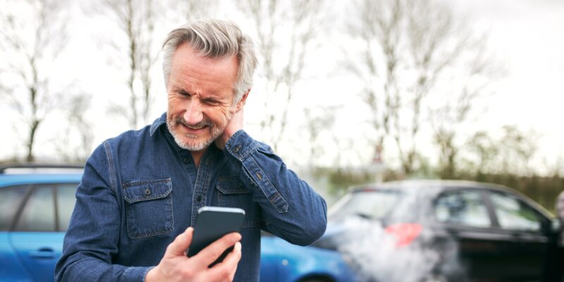 Male rubbing the back of his neck due to being injured in a car accident