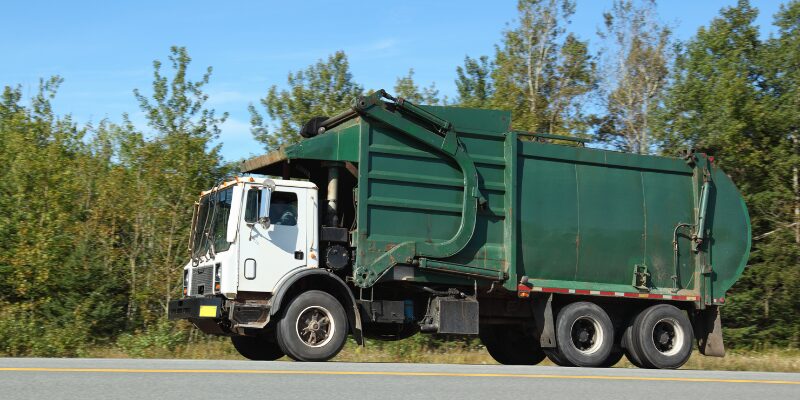 Municipal garbage green truck on the road