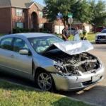 A police officer investigates a wrecked car's crumple zones