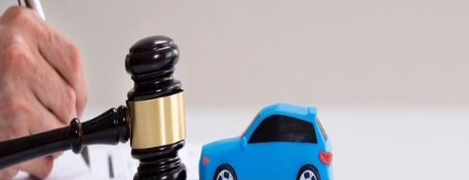 Gavel and toy car on a table, symbolizing car accident settlements and legal action.