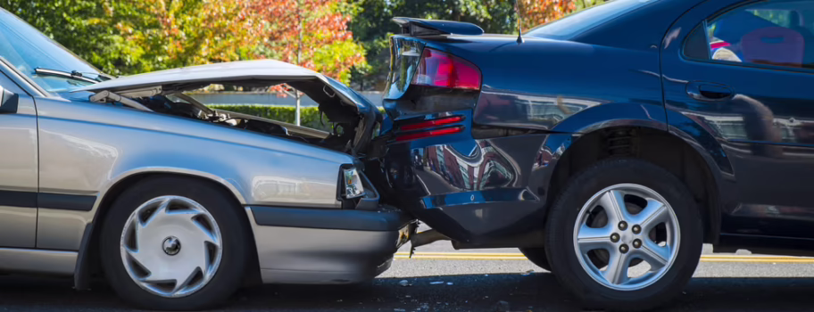 Two passenger vehicles involved in a rear-end collision on a road, showing significant front and rear damage.