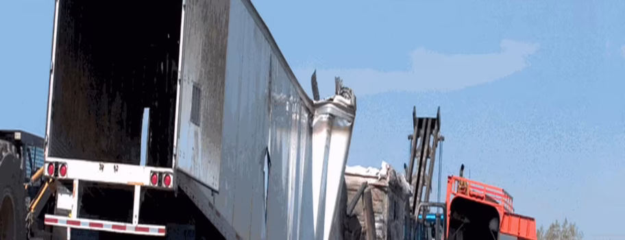 g9ngvsew3ufbeiti1xdq Damaged semi-truck trailer at an accident scene with workers and heavy equipment nearby.